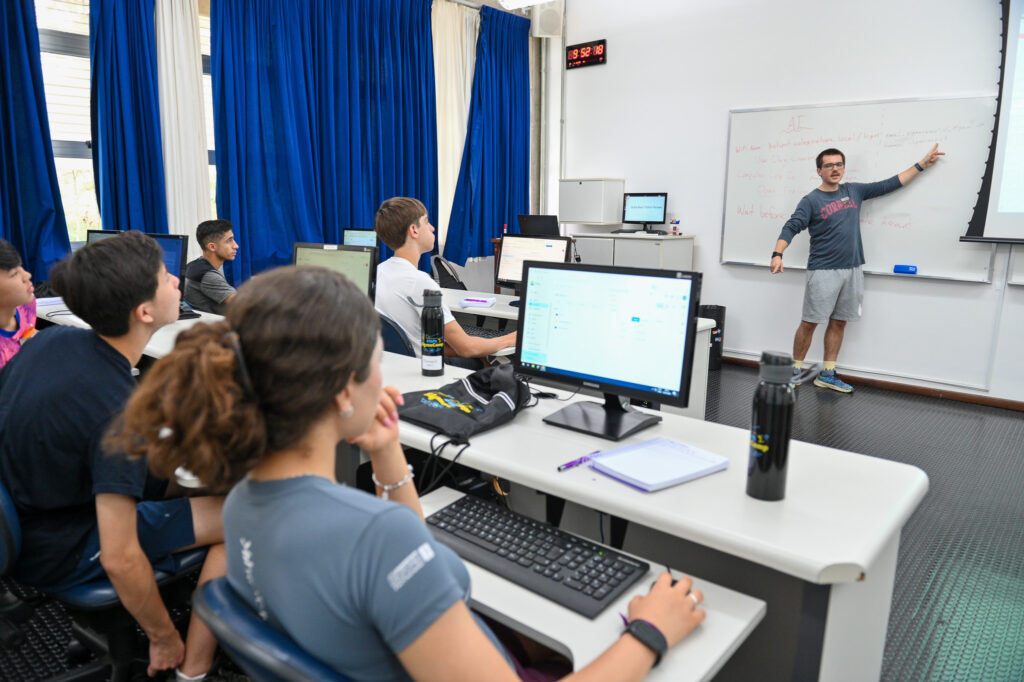 aula de computação, alunos olhando a lousa enquanto programam em suas telas