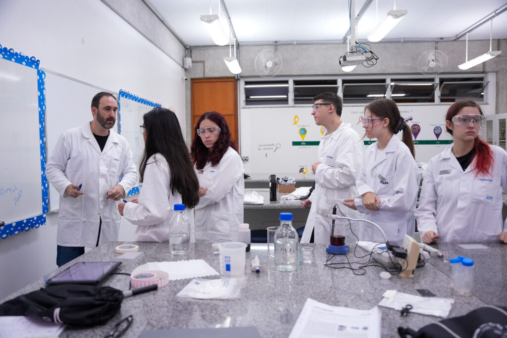 Aula em laboratótio, alunos e professores de jaleco