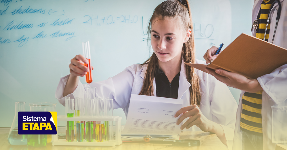 Estudante de química participando em uma atividade prática na sala de aula relacionada às olimpíadas de química IChO e IMChO, com laboratório de testes e anotações.