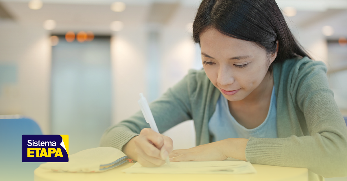 Estudante escrevendo redação com foco e concentração em ambiente de prova, representando a preparação para o Enem 2025.